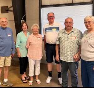 Mike Peterson, center, standing with a group of people indoors.