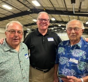 Mike Peterson standing with two men at a gathering, smiling for the photo.