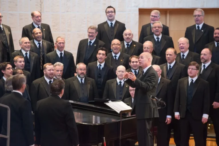 Members of the Orpheus Male Chorus of Phoenix singing with their conductor at the piano, inviting new singers to audition.
