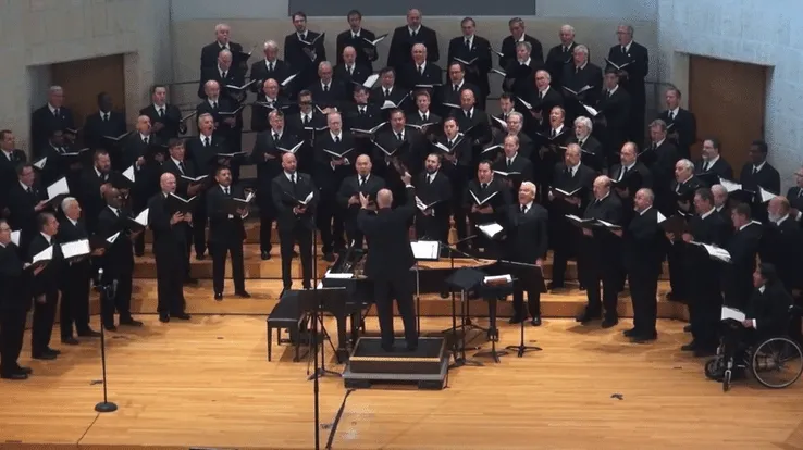 The Orpheus Male Chorus of Phoenix performing live in Paradise Valley with their conductor on stage.