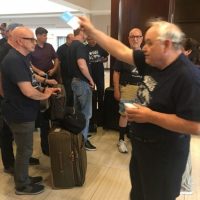 Bob Meier standing with a group, holding papers during a choir trip.