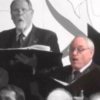 Bob Meier singing with a choir, holding a music folder.